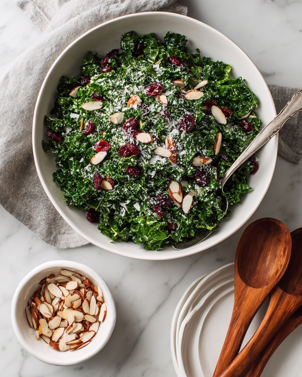 A large white bowl with a thin brown rim holds a fresh kale salad made of chopped dark green kale leaves, scattered with thin tan almond slices, small bright red dried cranberries, and light shavings of white cheese. To the left, a smaller white bowl with a brown rim contains more almond slices, some of which are spilled onto the white marbled surface below. On the right side, a stack of white plates with wood grain wooden serving spoons rests partly on the surface. Also on the right bottom corner, part of a grater, a small bowl of grated white cheese, and some grated cheese are visible on a wooden board, all atop the white marbled background. photo taken with an iphone --ar 4:5 --v 7