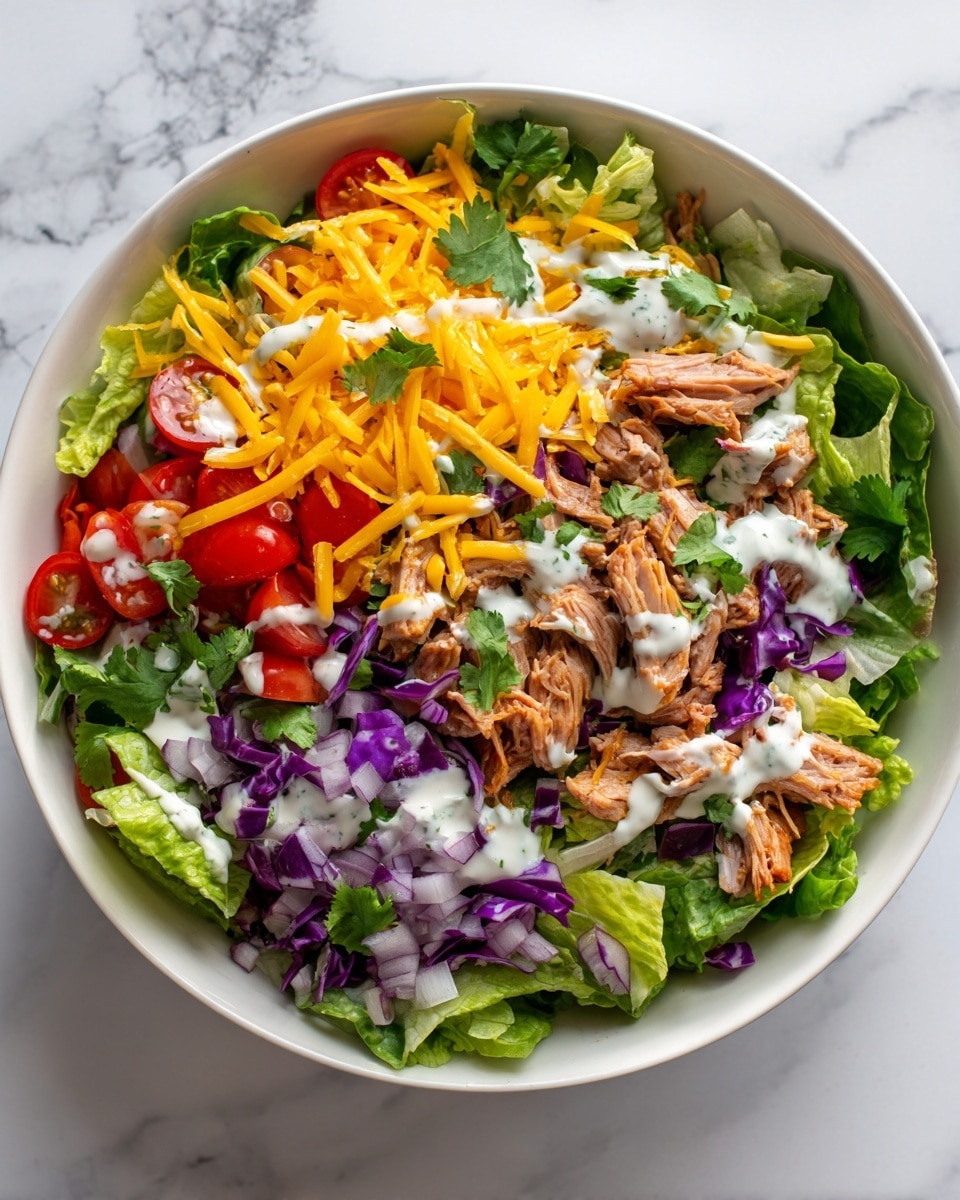 A white bowl filled with a colorful layered salad sits on a white marbled surface. The base layer is green leafy lettuce mixed with small pieces of purple cabbage and diced light purple onions. Above that, there are halved red cherry tomatoes scattered across. The top layer has shredded orange cheddar cheese and chunks of brown cooked meat, with small drizzles of white dressing on them for extra texture and color contrast. The salad looks fresh, full, and vibrant with a mix of red, green, purple, orange, and white colors. photo taken with an iphone --ar 4:5 --v 7