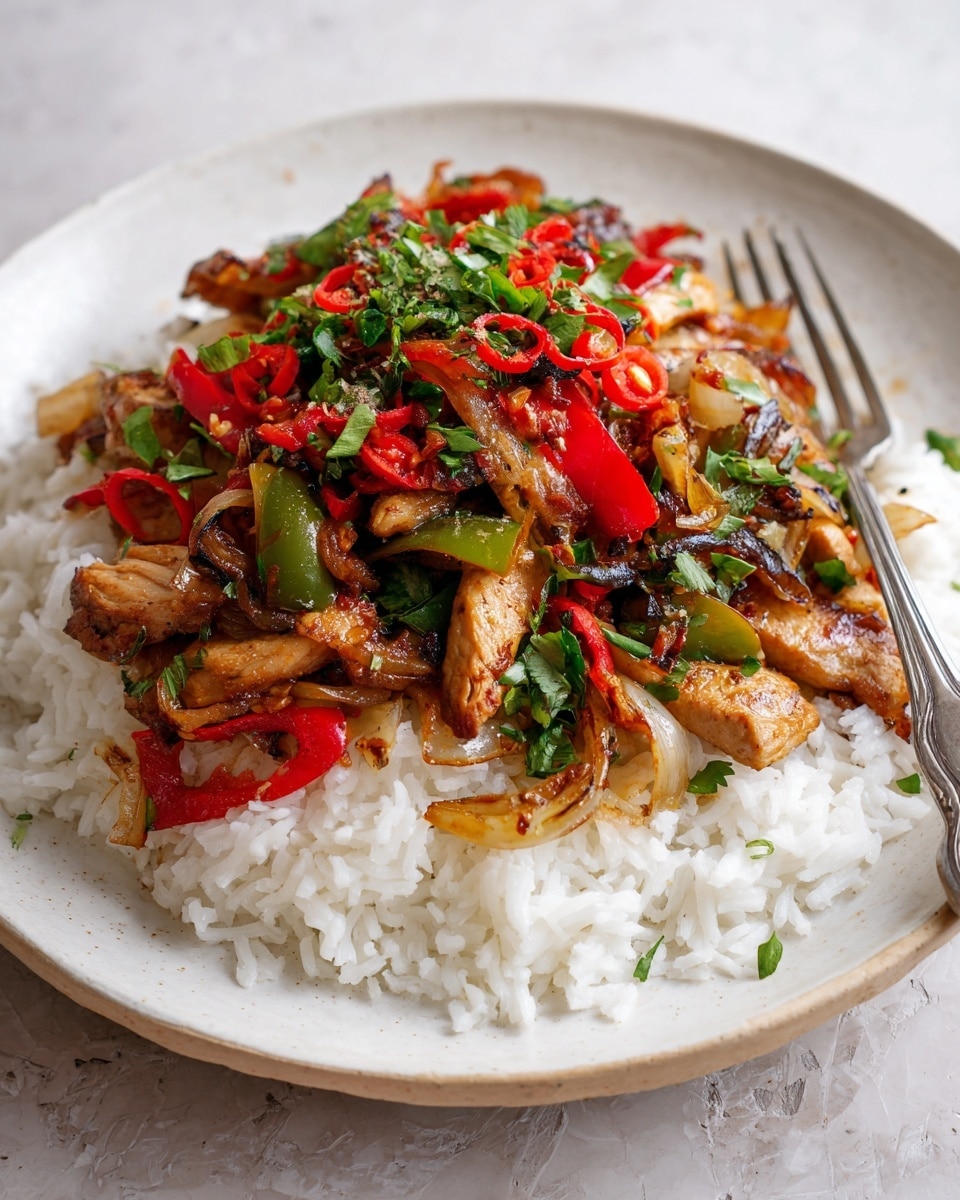 A white plate holds a bed of soft white rice as the first layer, topped with a colorful mix of grilled vegetables including red and green bell peppers and light brown onions. On top of the vegetables are pieces of cooked chicken with a browned, slightly charred texture. Bright green chopped herbs and small pieces of red chili are sprinkled all over the dish, adding freshness and a pop of color. A silver fork rests on the side of the plate against a white marbled background. photo taken with an iphone --ar 4:5 --v 7