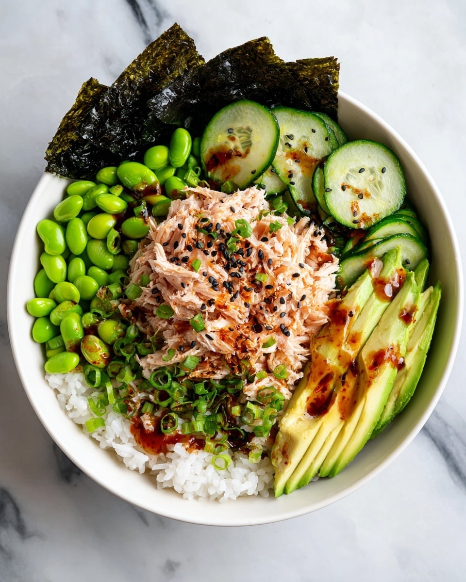 A white bowl filled with three main layers starting with a base of white rice. On top of the rice, there are several slices of cooked zucchini that are yellow with a bit of brown char, bright green edamame beans, and shredded light pink tuna mixed with sauce. On one side, thin slices of bright green avocado are fanned out. Two dark brown seaweed sheets lean against the bowl’s inner edge. The whole dish is sprinkled with red chili flakes, black sesame seeds, and small green onion pieces. The bowl sits on a white marbled surface. photo taken with an iphone --ar 4:5 --v 7