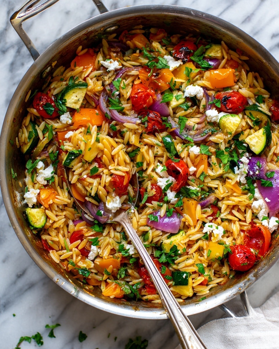 A close-up view of a silver metal pot filled with orzo pasta mixed with grilled vegetables including orange bell peppers, zucchini, cherry tomatoes, and pieces of red onion. The orzo is light golden brown and the vegetables show some char marks. White crumbled cheese is scattered on top along with fresh green herbs. A spoon is scooping a portion from the pot, holding a colorful mix of shiny pasta and vegetables. The pot is placed on a white marbled surface with a white cloth partially visible on the right side. Photo taken with an iphone --ar 4:5 --v 7