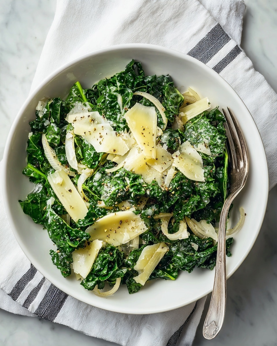A white bowl is filled with a fresh green salad, made up of large, leafy kale pieces with a slightly wrinkled texture. Thin rings of light beige onion are scattered on top, along with thin slices of pale yellow cheese shavings. The salad is lightly sprinkled with small black pepper grains and is dressed with a light vinaigrette, making the kale look shiny. A silver fork is placed inside the bowl on the right side, and the bowl sits on a white marbled surface with a white cloth featuring thin black stripes peeking from the lower part of the image. Photo taken with an iphone --ar 4:5 --v 7
