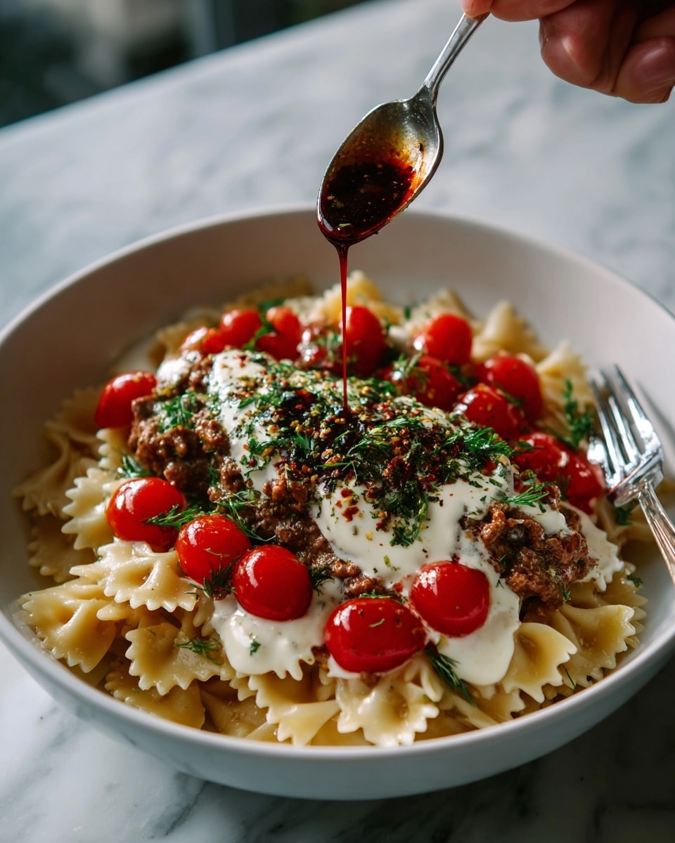 A white bowl filled with farfalle pasta as the base layer, light yellow in color with a soft texture. On top of the pasta is a thick layer of white creamy sauce, smooth and spread evenly. Over the cream, there is a generous layer of cooked minced meat, dark brown and crumbly with bits of seasoning. On top of the meat, several halved cherry tomatoes, bright red with a juicy texture, are sprinkled with dried herbs that add a green contrast. A fork with a white handle rests on the edge of the bowl. In the background on a white marbled surface, there is another similar bowl partially visible with the same dish, a small bowl with reddish-brown spice, and a speckled gray bowl with white yogurt sauce. Photo taken with an iphone --ar 4:5 --v 7