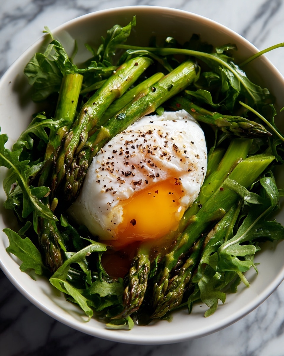 A white bowl filled with bright green arugula leaves, topped with short stalks of cooked asparagus, and a single poached egg placed in the center. The egg has a white outer layer with the yolk slightly broken, showing a rich yellow, slightly runny center sprinkled with black pepper. The bowl sits on a white marbled surface. Photo taken with an iphone --ar 4:5 --v 7