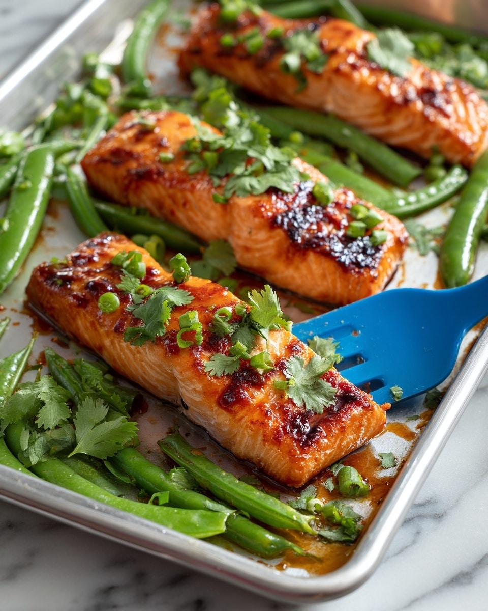 Three medium-sized cooked salmon fillets with a bright orange color and slightly charred edges are placed on a metal baking sheet, each fillet topped with small green cilantro leaves and slices of light green scallions. Fresh green snap peas with a glossy texture fill the spaces around the salmon. The metal baking sheet holds the salmon and peas on a white marbled surface. A blue spatula lifts the middle salmon fillet, showing its moist texture with some sauce underneath. photo taken with an iphone --ar 4:5 --v 7