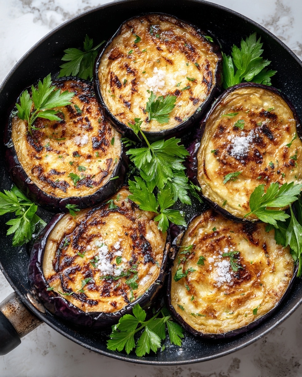 The image shows a close-up of six grilled eggplant slices arranged in a black pan. Each slice has a golden-brown, slightly charred surface with visible grill marks and some coarse salt sprinkled on top. Bright green sprigs of parsley are scattered around and on the eggplant for garnish. The pan is partially visible with a metal handle on one side, and the background has a white marbled texture. photo taken with an iphone --ar 4:5 --v 7