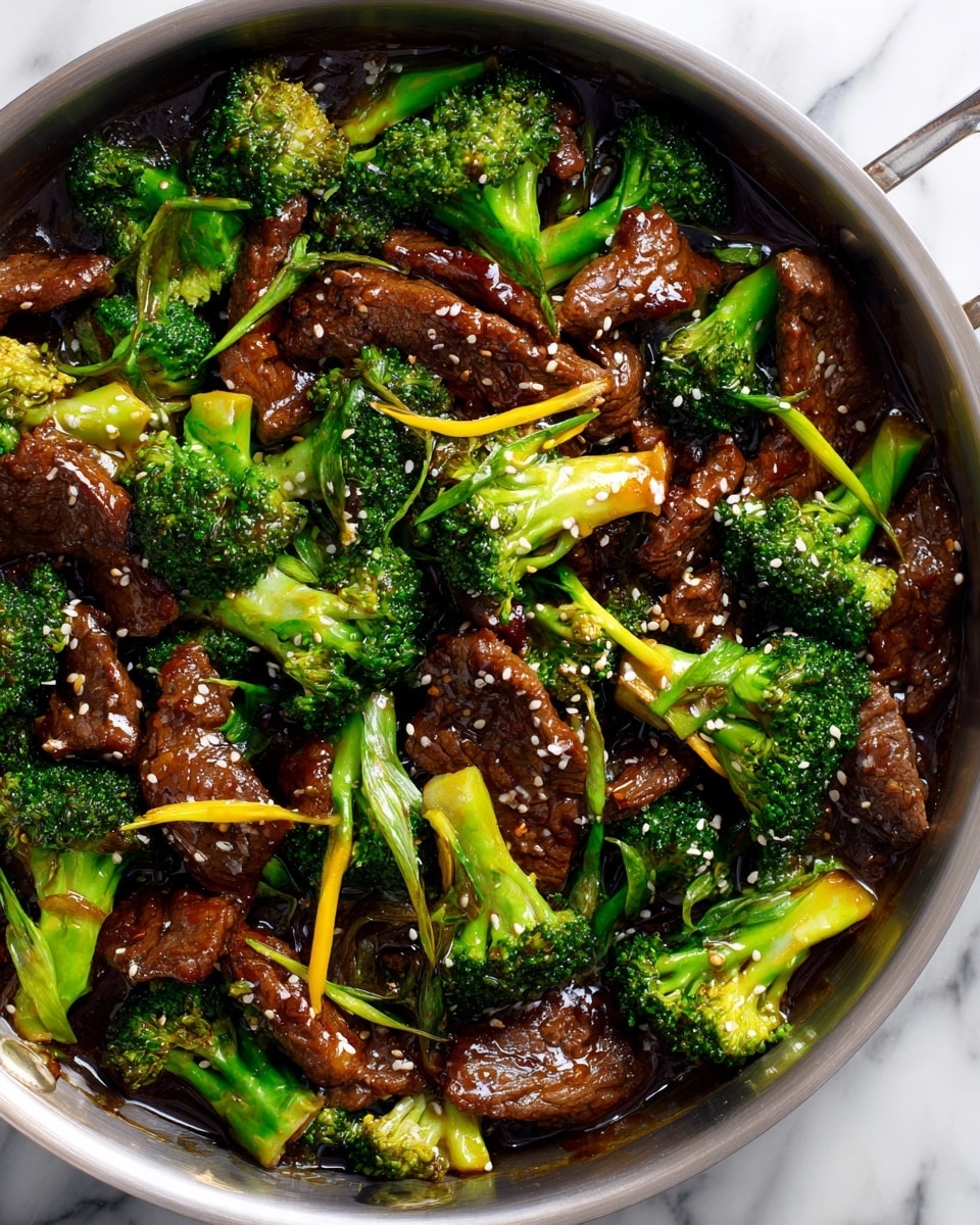 A close-up view inside a silver pan shows a dish with two main layers: bright green broccoli florets and brown slices of beef, all coated in a shiny dark brown sauce. The broccoli is fresh and tender, spread evenly throughout, mixed with thin green onion pieces, while the beef pieces vary in size and are tender-looking. The dish is sprinkled lightly with small white sesame seeds on top. The pan sits on a white marbled surface, and there is no other decoration in the picture. Photo taken with an iphone --ar 4:5 --v 7