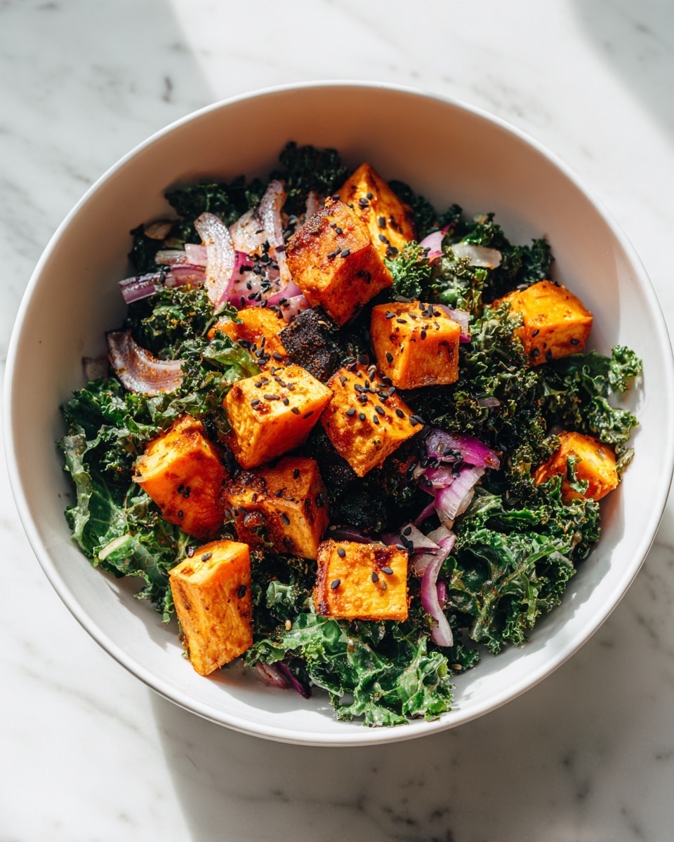 A white bowl holds a layered salad with two main layers: the bottom layer is dark green, curly kale leaves with a slightly rough texture, and mixed in small pieces of red onion adding purple accents. On top, there are evenly spread golden-orange roasted cubes, each with a crispy, browned surface that shines slightly, showing slight grill marks and seasoning specks. The salad sits on a white marbled surface with soft light reflecting off the bowl’s smooth edges. photo taken with an iphone --ar 4:5 --v 7