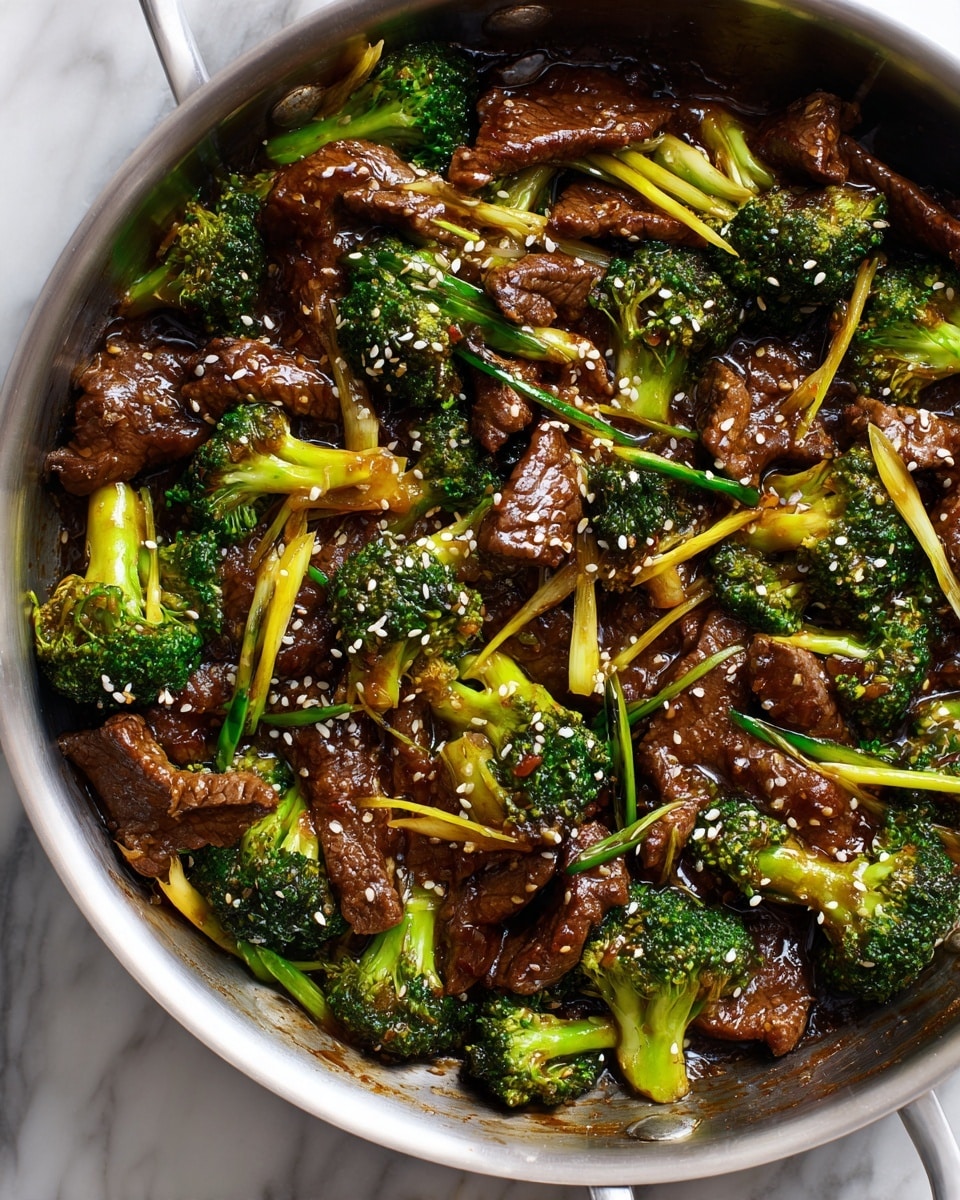 A metal pan filled with a glossy dark brown stir-fry sauce covering medium-sized pieces of tender beef and bright green broccoli florets scattered evenly throughout. The beef pieces are thin and slightly curled with a shiny, caramelized texture. The broccoli has a fresh, slightly crisp look with a vibrant green color. Small yellowish chili or pepper slices are mixed in, giving a pop of light color. The dish is sprinkled with tiny white sesame seeds for texture. The pan sits on a white marbled surface. Photo taken with an iphone --ar 4:5 --v 7