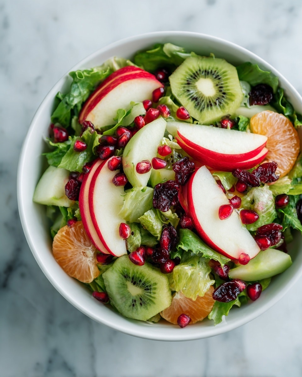 The image shows a white bowl filled with a colorful fruit and spinach salad. The base layer is bright green spinach leaves, fresh and leafy. On top of the spinach, there are slices of orange mandarin, small red and white pieces of apple, and light green slices of kiwi. Scattered throughout the salad are dark red dried cranberries and shiny red pomegranate seeds. The bowl sits on a white marbled surface. Photo taken with an iphone --ar 4:5 --v 7