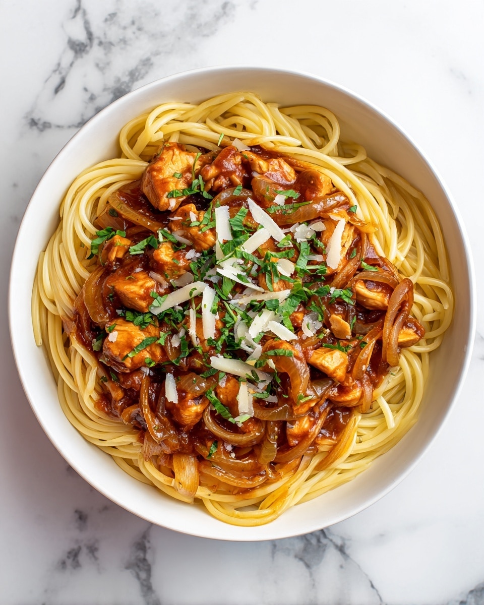 A white bowl filled with spaghetti noodles that are tan and glossy, twisted around each other. Scattered over the noodles are pieces of golden-brown cooked chicken chunks covered in a thick orange-red sauce mixed with translucent cooked onions. Small green parsley leaves are sprinkled on top for color, along with white grated cheese lightly dusted over the whole dish. The bowl sits on a white marbled surface. photo taken with an iphone --ar 4:5 --v 7