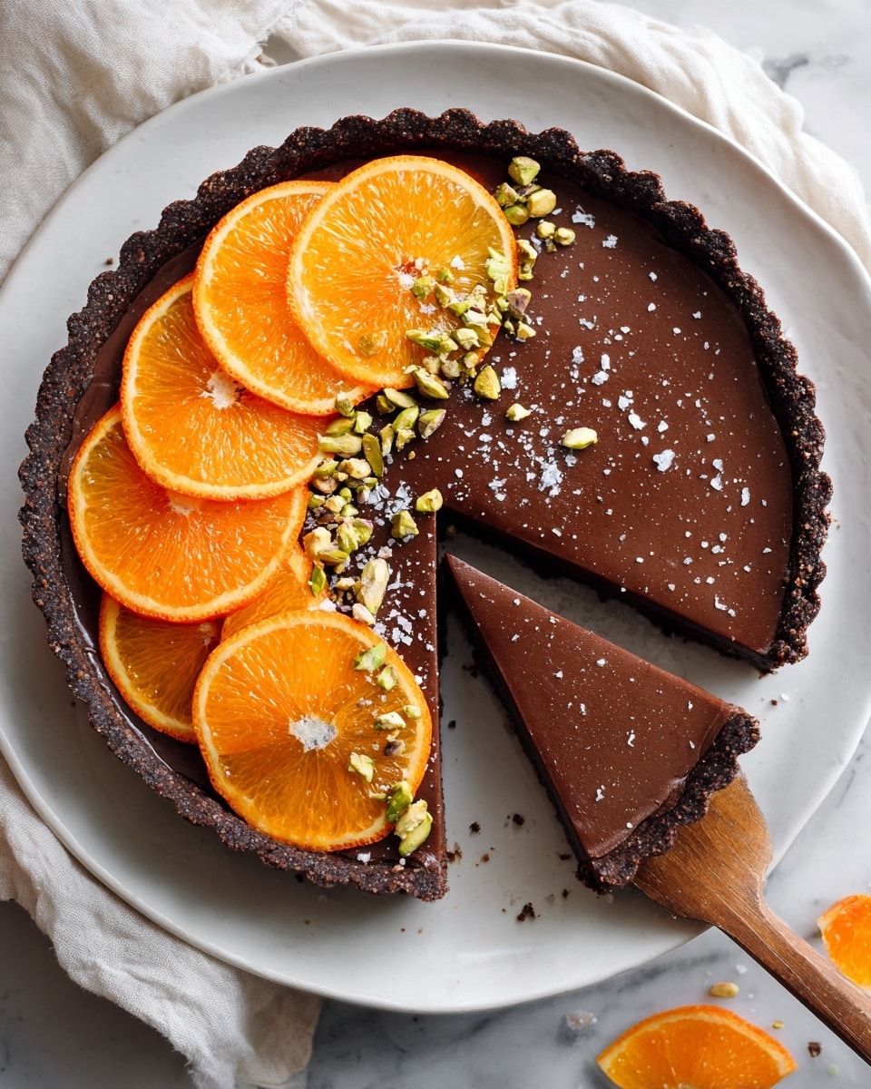 A round tart with three layers: the bottom crust is dark brown and crunchy, the middle filling is smooth dark chocolate with a matte texture, and on top, orange slices with bright yellow-orange peel are arranged on the left side, layered and slightly overlapping, garnished with small bright green chopped pistachios and a few coarse salt grains scattered near the tart edge. One slice has been removed and is held by a wooden spatula coming from the bottom right. The tart rests on a white plate placed on a white marbled surface with some small bowls of spices and orange slices around. Photo taken with an iphone --ar 4:5 --v 7