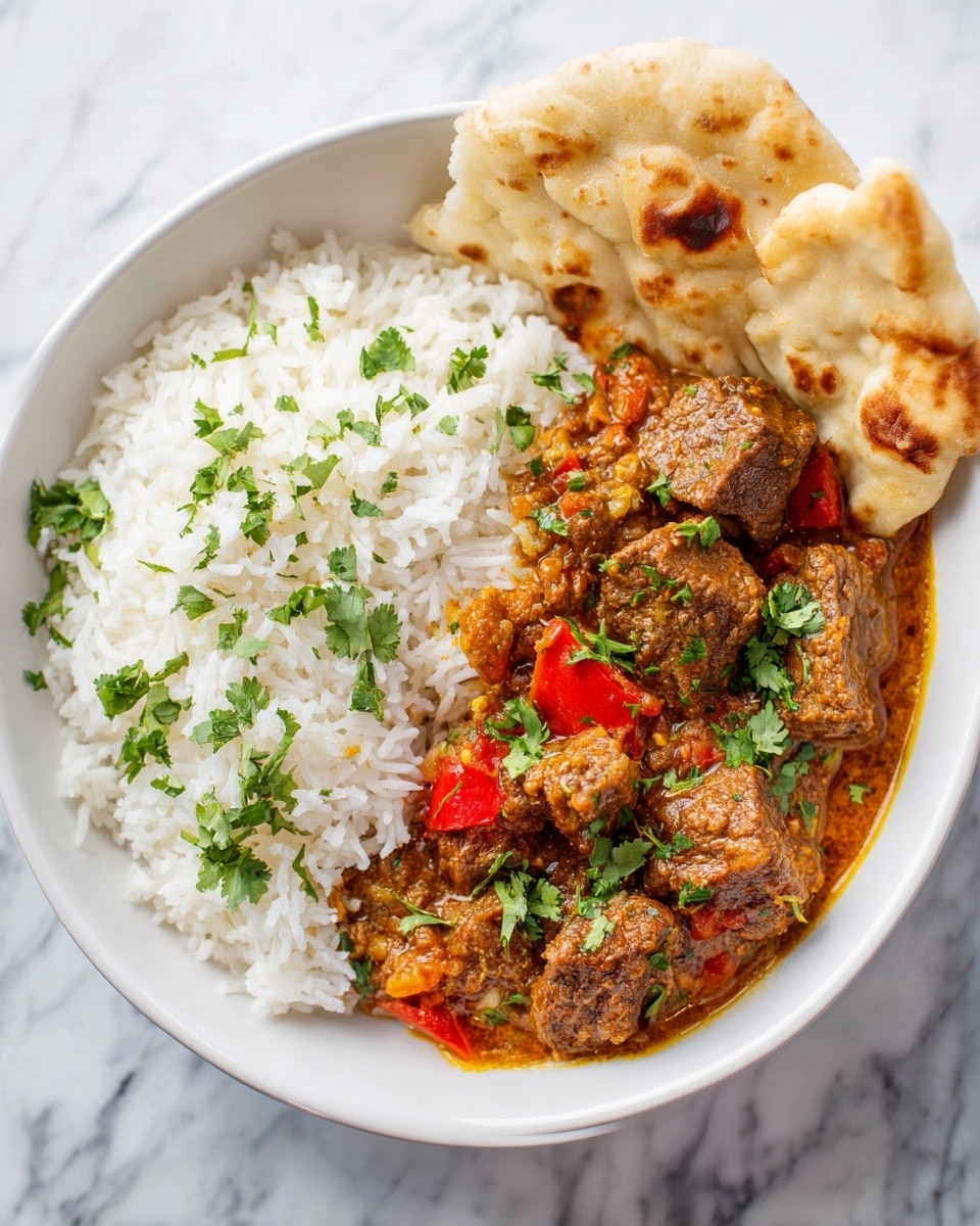 A white bowl sits on a white marbled surface filled with two main layers. On the left side, there is a mound of white rice topped with scattered fresh green cilantro leaves. On the right side, thick pieces of brown meat stew in a rich, dark orange-brown sauce with visible small red pieces, garnished with more cilantro leaves. In the back of the bowl, there are two pieces of torn flatbread resting on the edge. The photo taken with an iphone --ar 4:5 --v 7