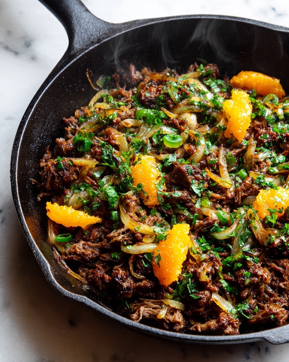 This image shows a close-up of a black cast iron skillet filled with shredded, dark brown cooked meat mixed with caramelized yellow onion slices and orange and lime wedges scattered throughout. The meat looks juicy and tender with a slightly glossy texture, and small green cilantro leaves are sprinkled over the top. Steam rises gently from the hot dish, enhancing the freshly cooked feel. The skillet sits on a white marbled surface. photo taken with an iphone --ar 4:5 --v 7